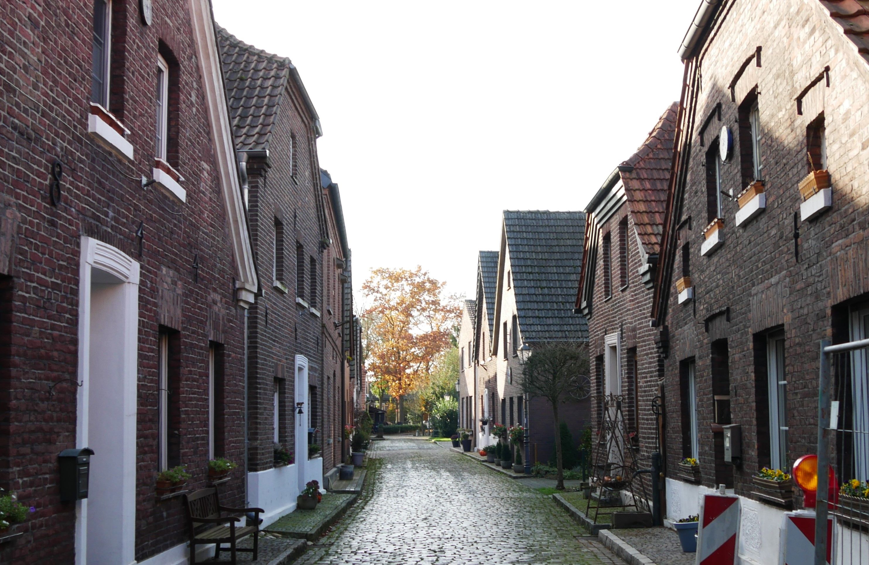 Jens Nieweg, Tourismus NRW e.V., Kleine Backsteinhäuschen säumen Kopfsteinpflaster-Straße in Hünxe-Krudenburg