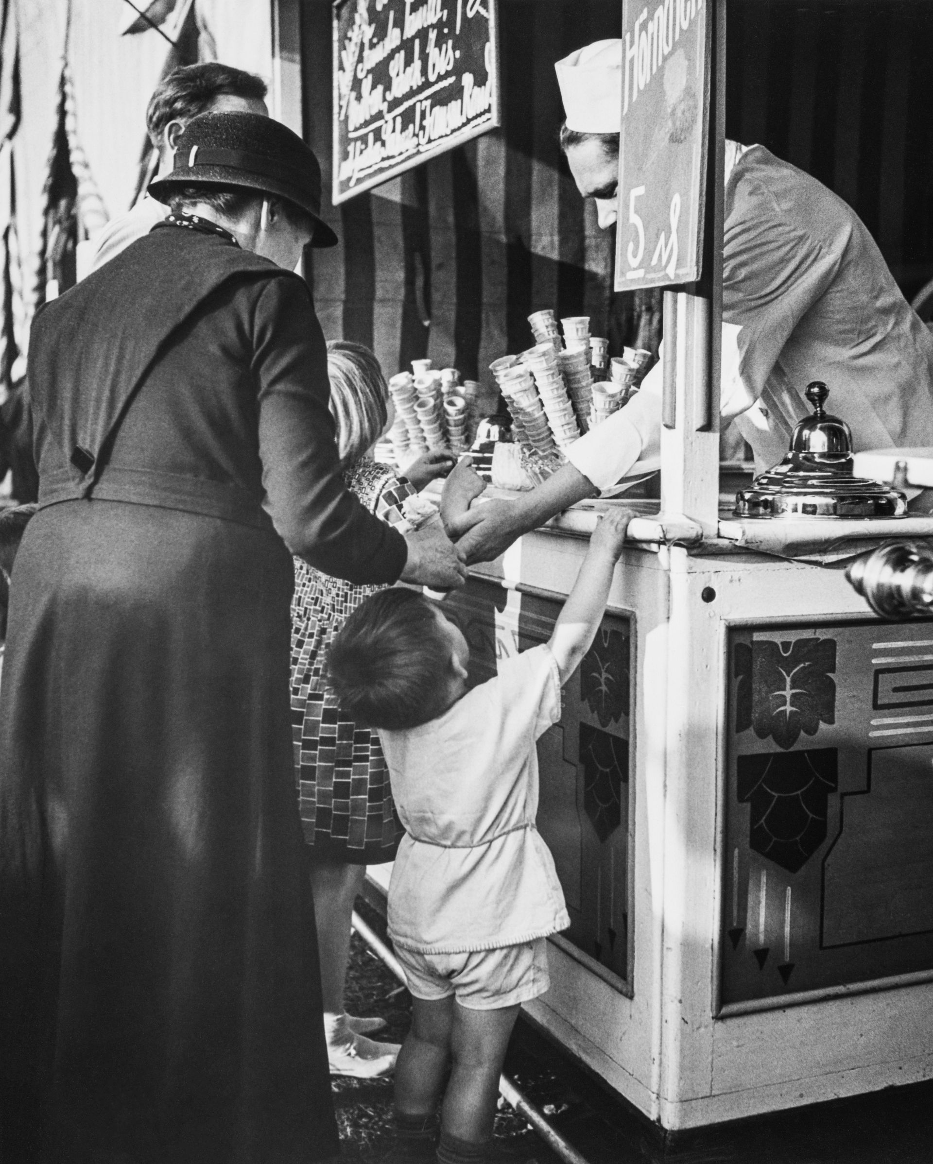 Child stands with his grandma in front of the ice cream vendor