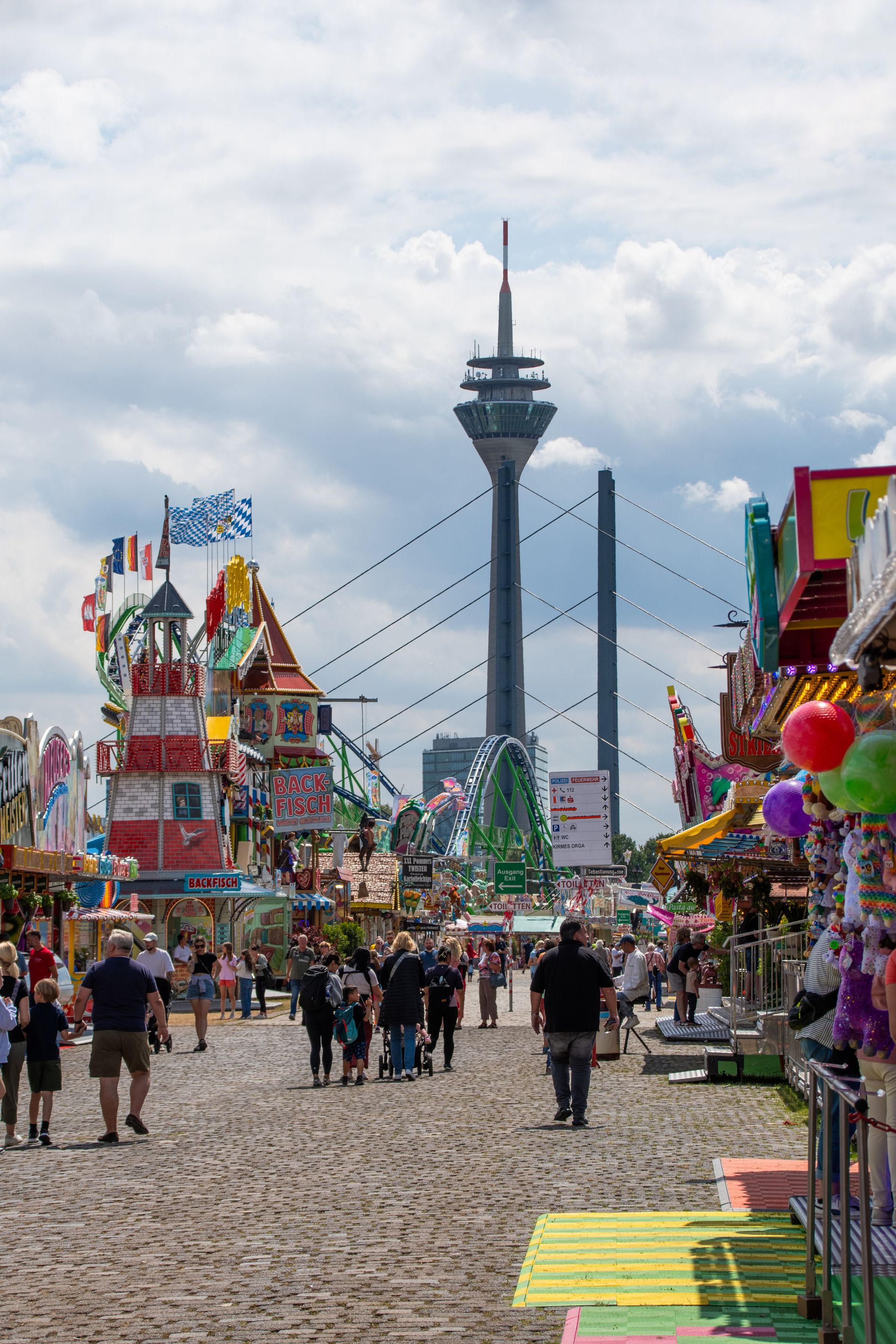 The Düsseldorf television tower rises up between the rides and food stalls at the Rhine funfair