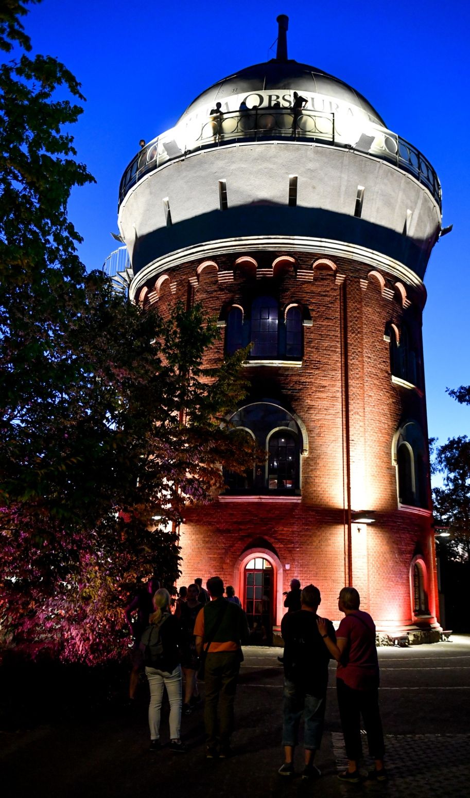 In the evening, lights illuminate the railroad water tower built in 1904 in the middle of MüGa Park